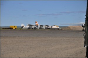 Chokurdakh airfield populated with Antanov (AN-2, AN-4?, AN-24) aircraft as well as a MI-8 helicopter. The wingtip to the right is our (cargo-)aircraft (Antanov AN-26-100) with luggage self-loading (Photo: M. Schaepman, July 2013).